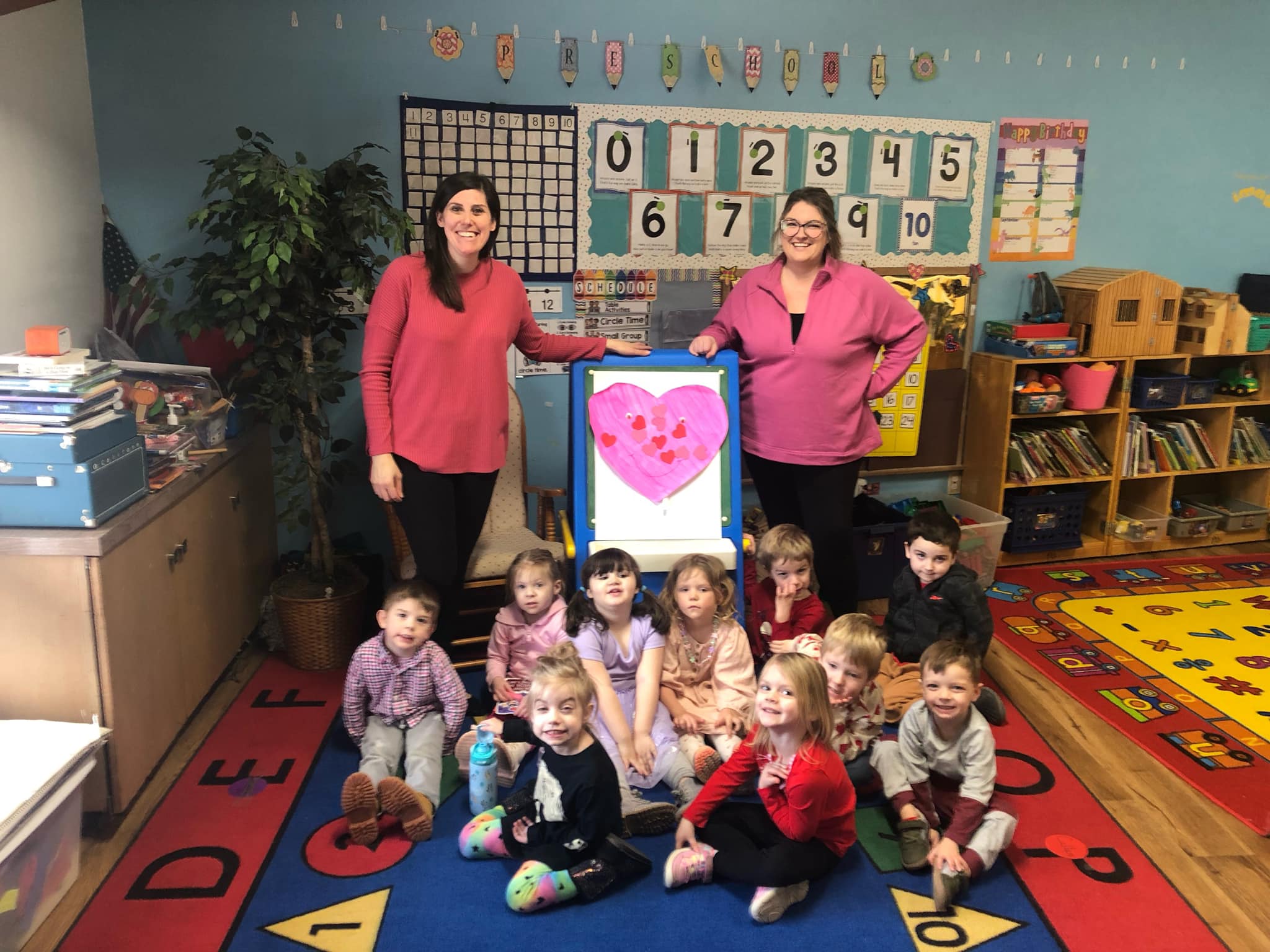 Children sitting on floor in front of teachers at HCNS