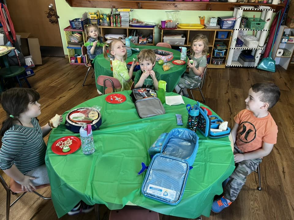 Children sitting around table enjoying snack time at HCNS